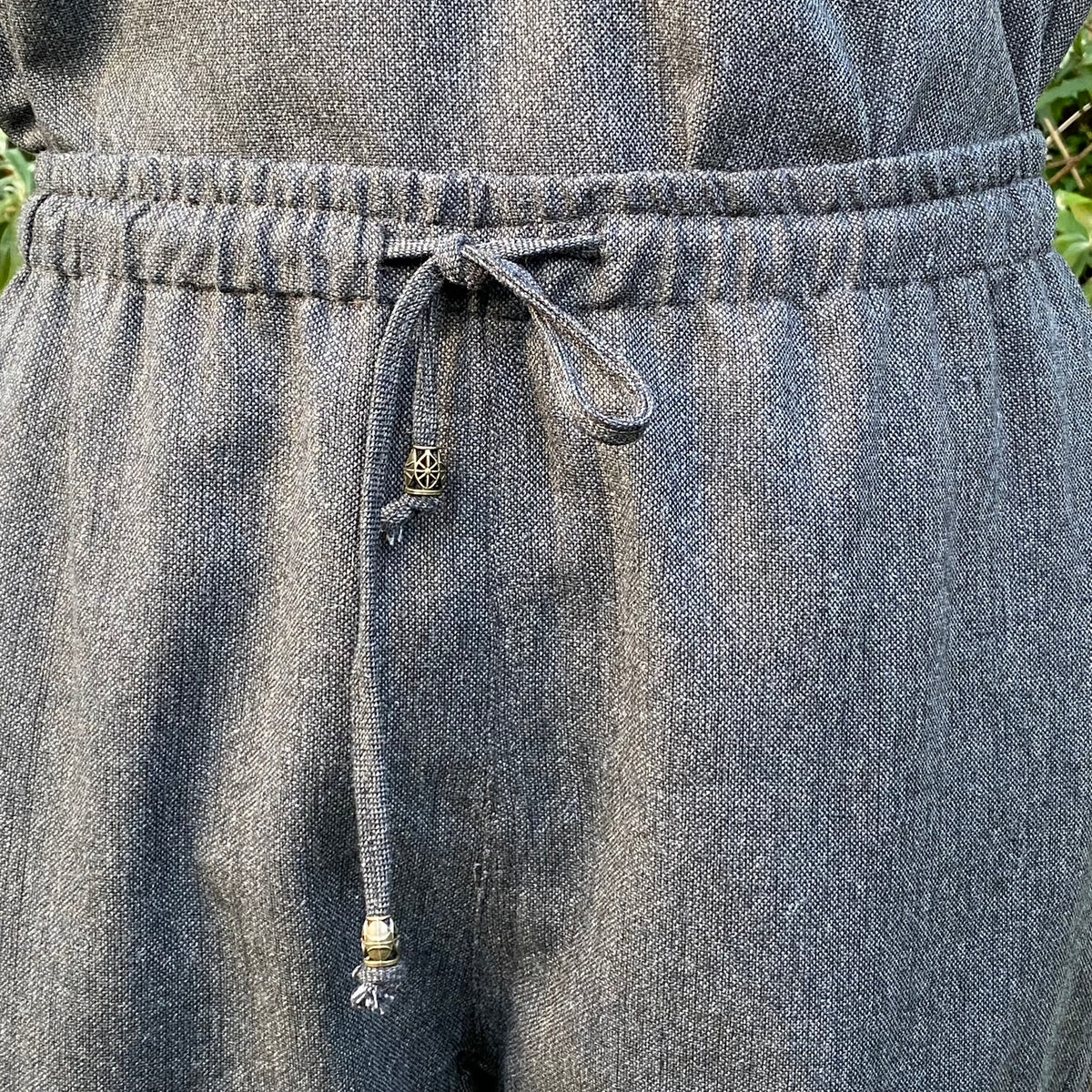 Close-up detail of wool fabric and drawstring on grey medieval trousers.