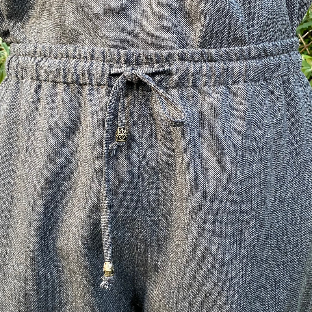 Close-up detail of wool fabric and drawstring on grey medieval trousers.