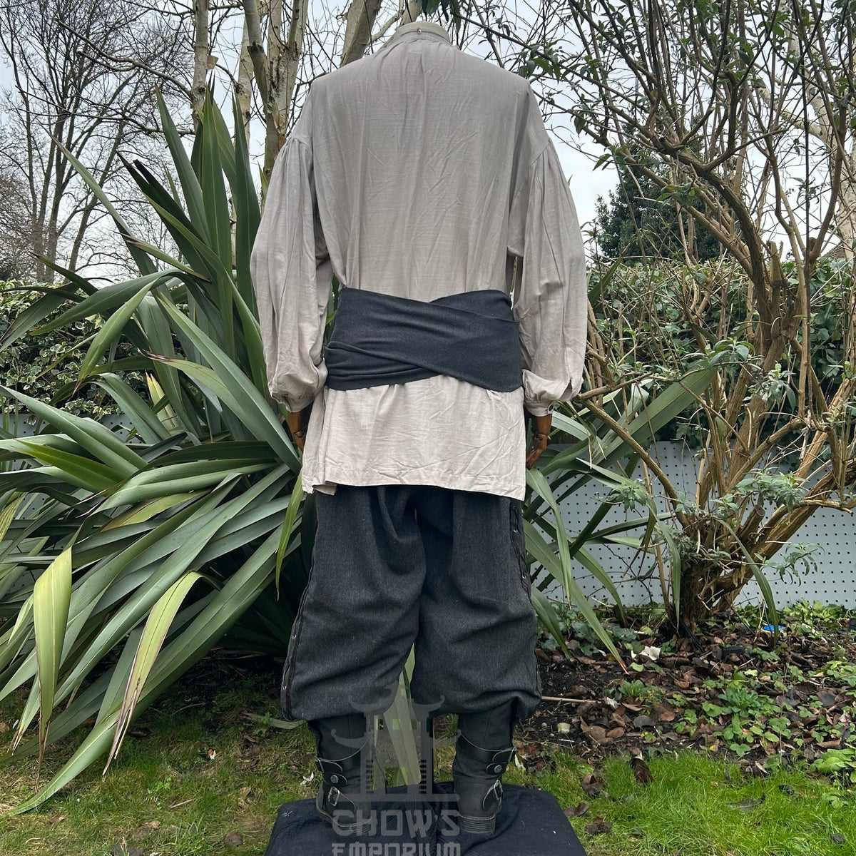 Back view of medieval LARP set with grey shirt, black sash, dark trousers.