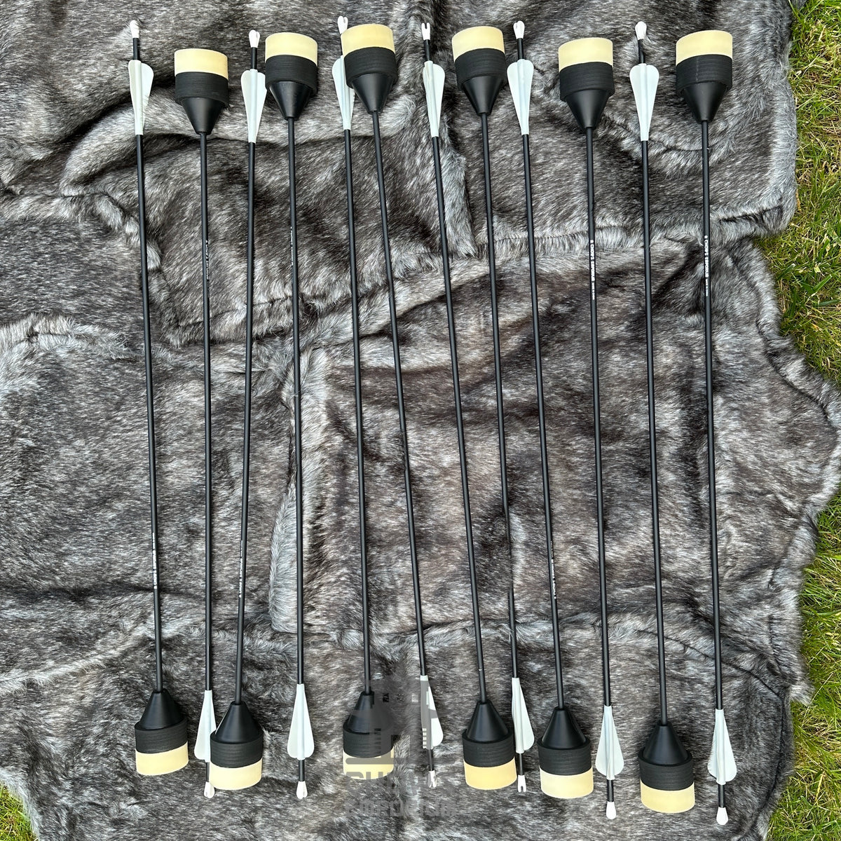 Set of black arrows with yellow nocks on a camouflage-patterned fabric background.