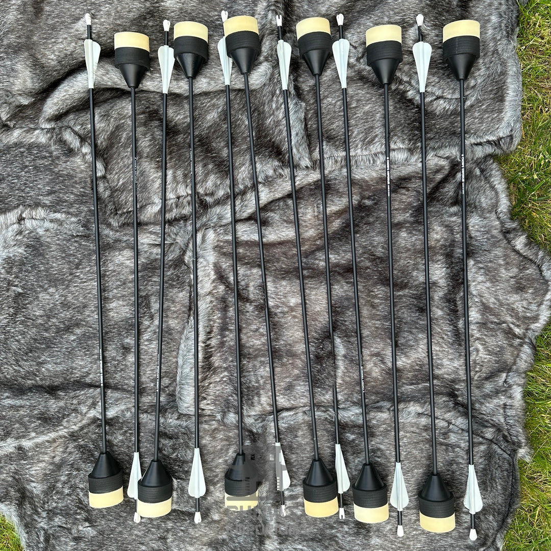 Set of black arrows with yellow nocks on a camouflage-patterned fabric background.