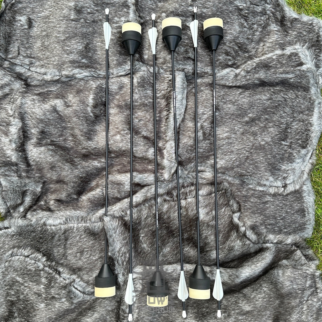 Set of six black and white archery nocks on a camouflage-patterned background.