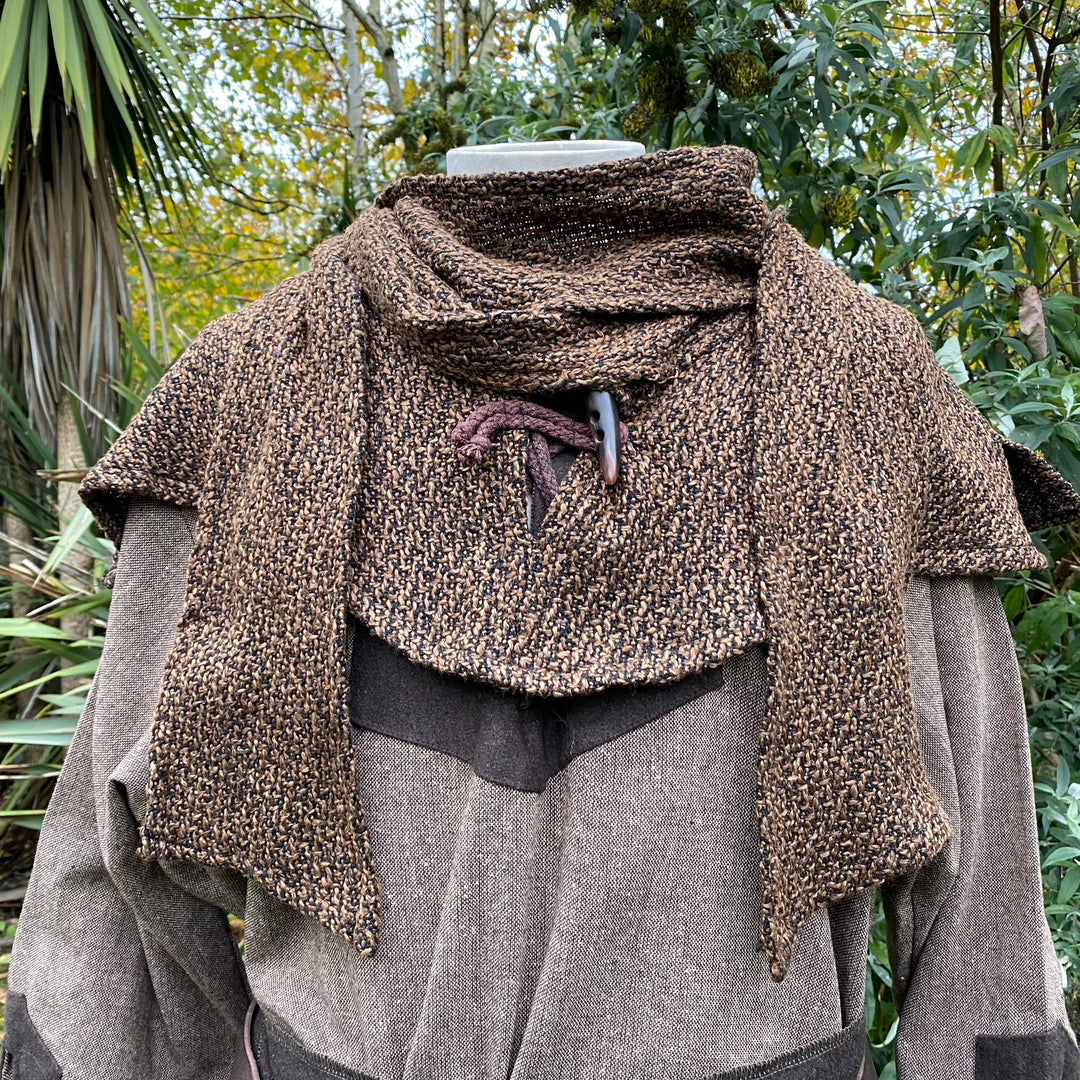 Brown wool scarf hood draped over mannequin in medieval LARP setting.