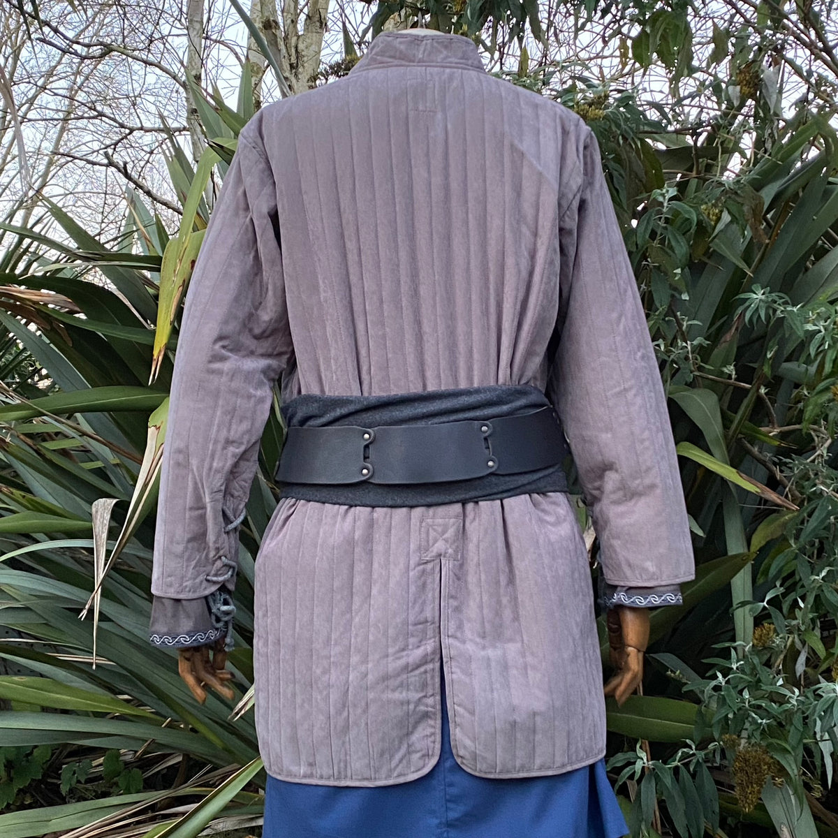 Back view of grey medieval gambeson with black belt, LARP setting.