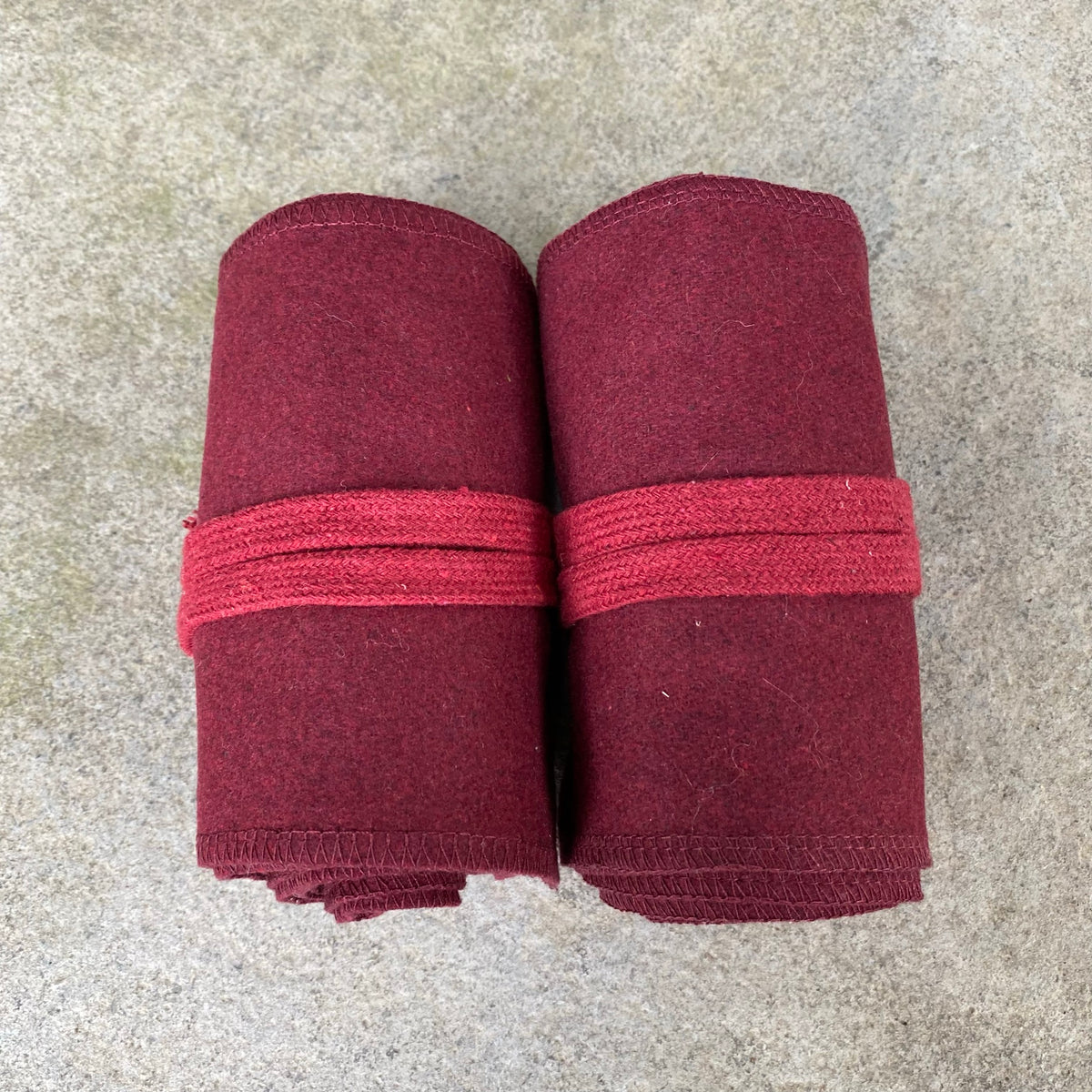Two rolled red wool wraps for LARP, top view displaying texture.