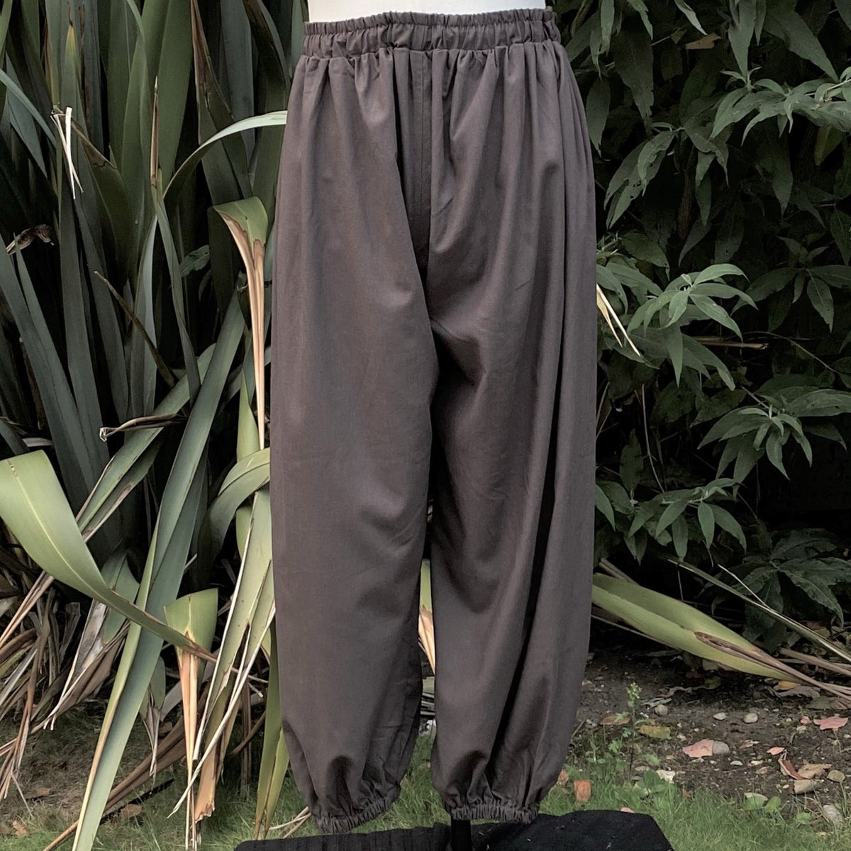 Grey medieval LARP pants front view, gathered waist, ankle cuffs.