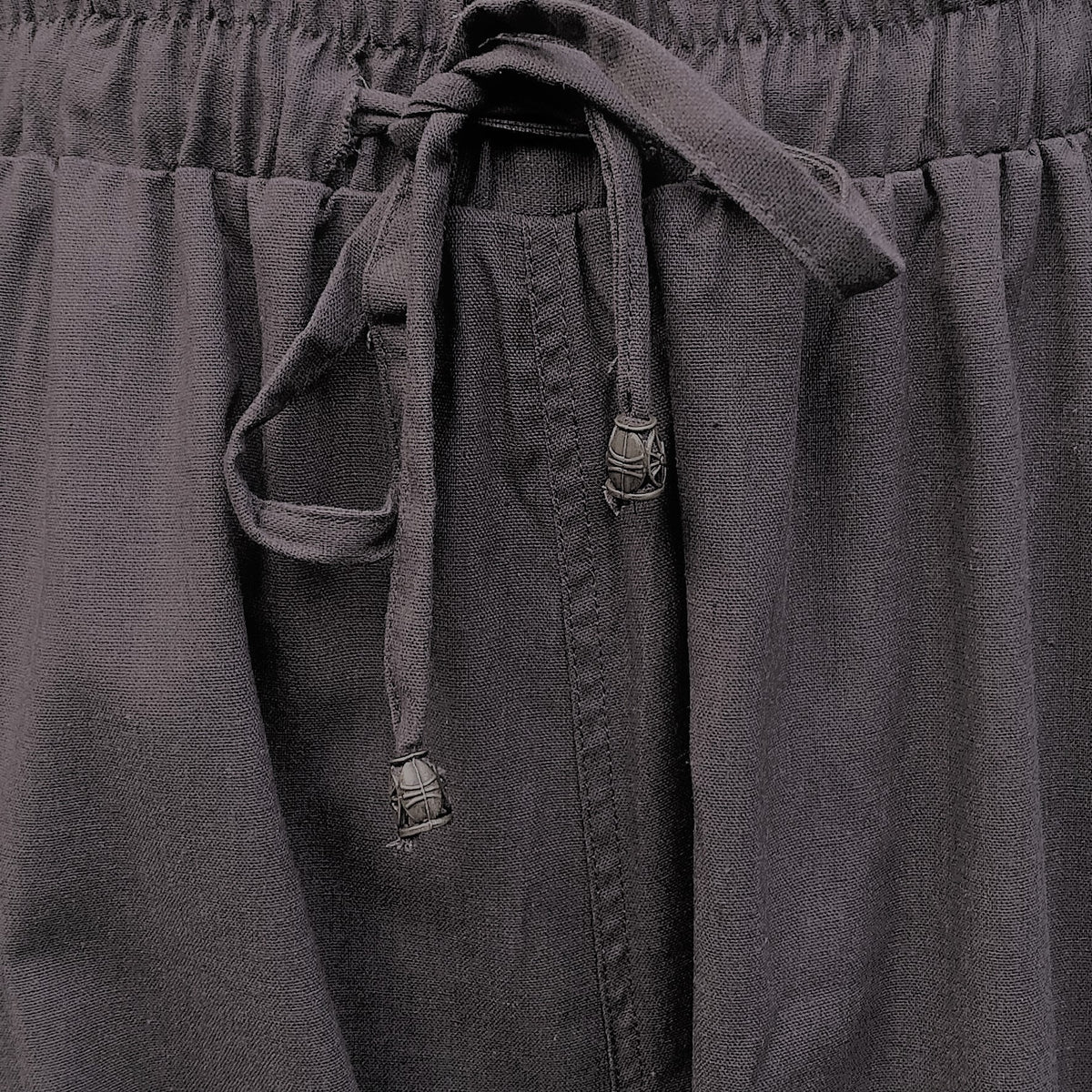 Detail shot of reinforced stitching and fabric texture on grey medieval trousers.