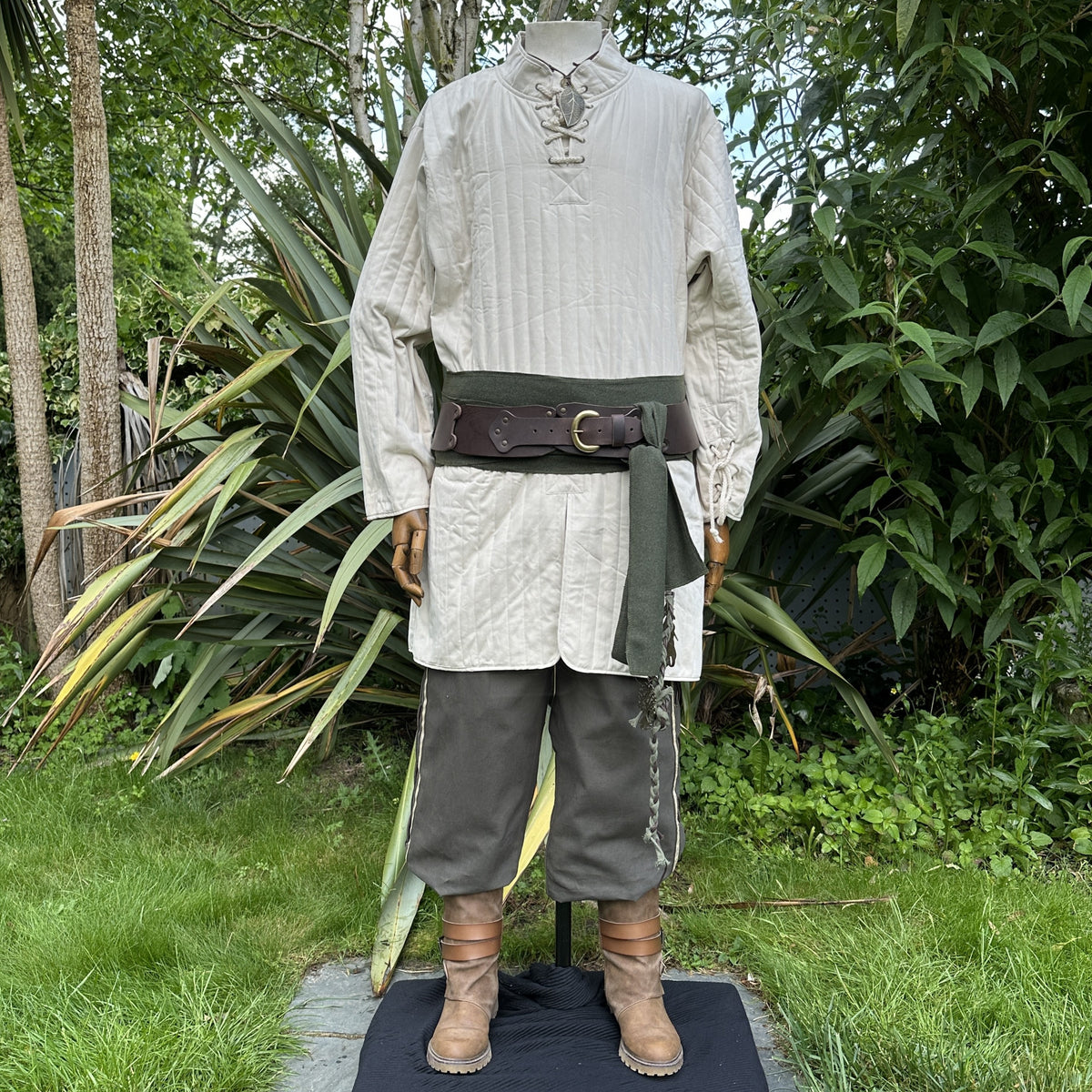 3 piece outfit with white padded gambeson, and green trousers and sash.