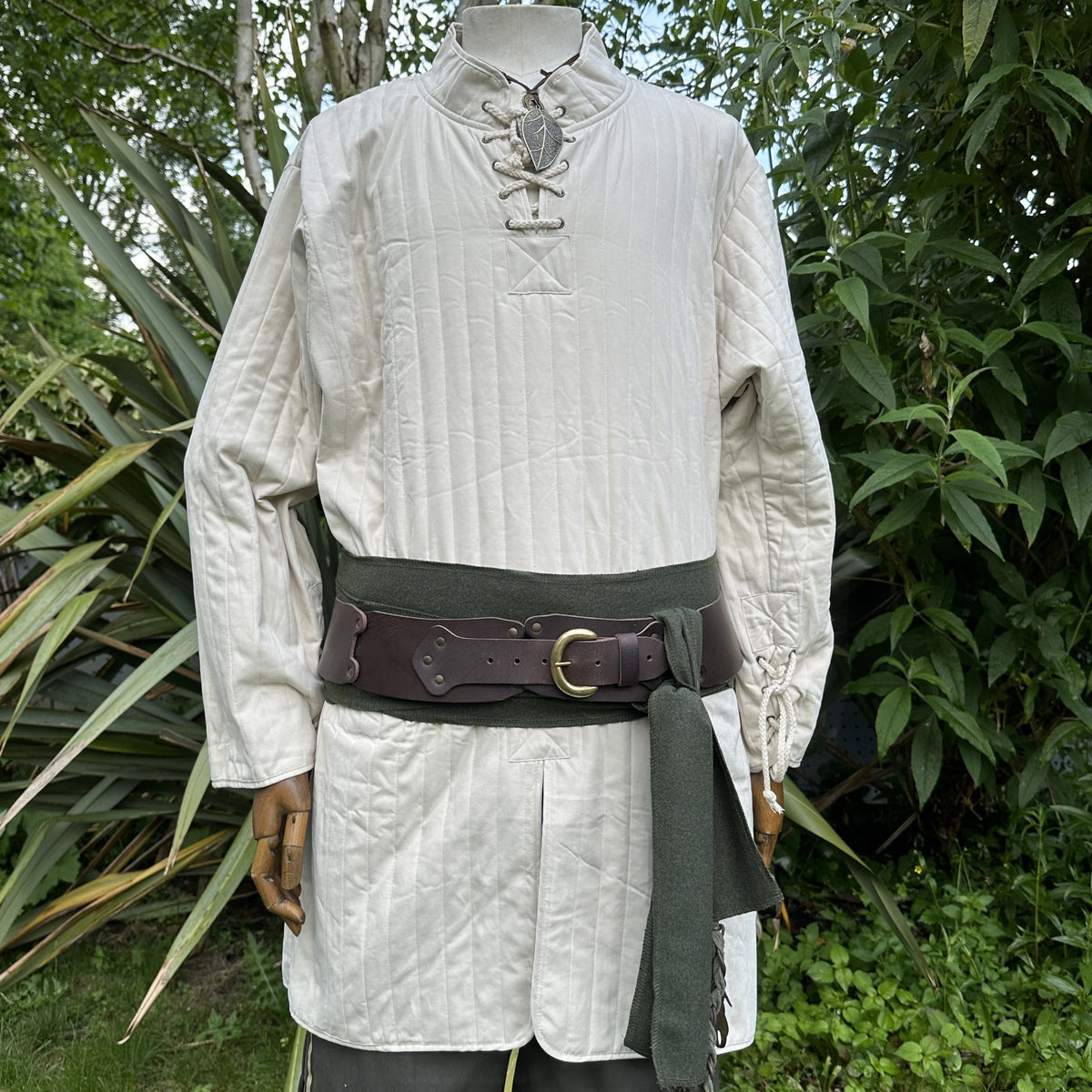 White quilted medieval gambeson with green sash, leather belt.