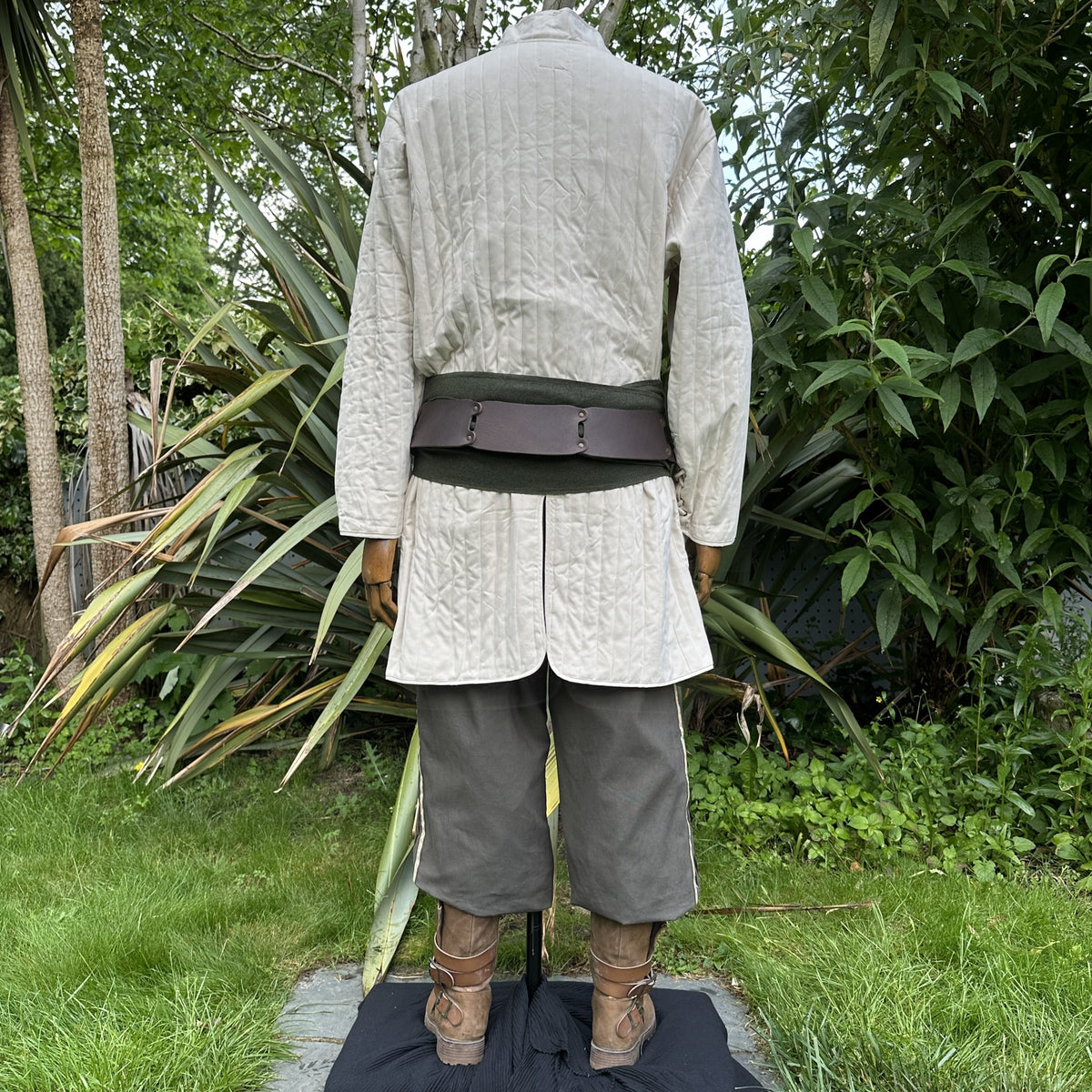 LARP medieval outfit with white gambeson, grey pants, and brown sash, rear view.
