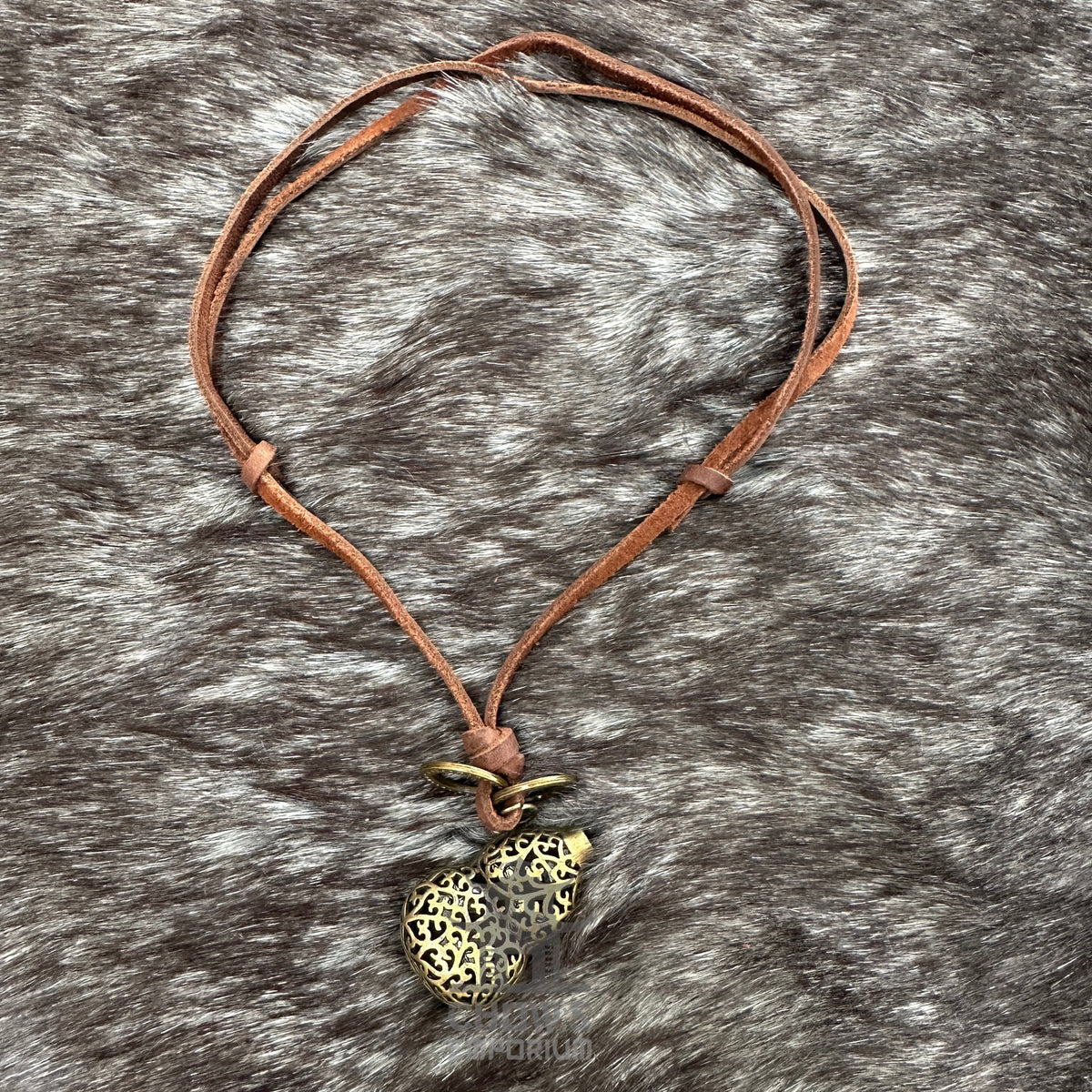 LARP fish orb necklace with brown leather cord on textured background.