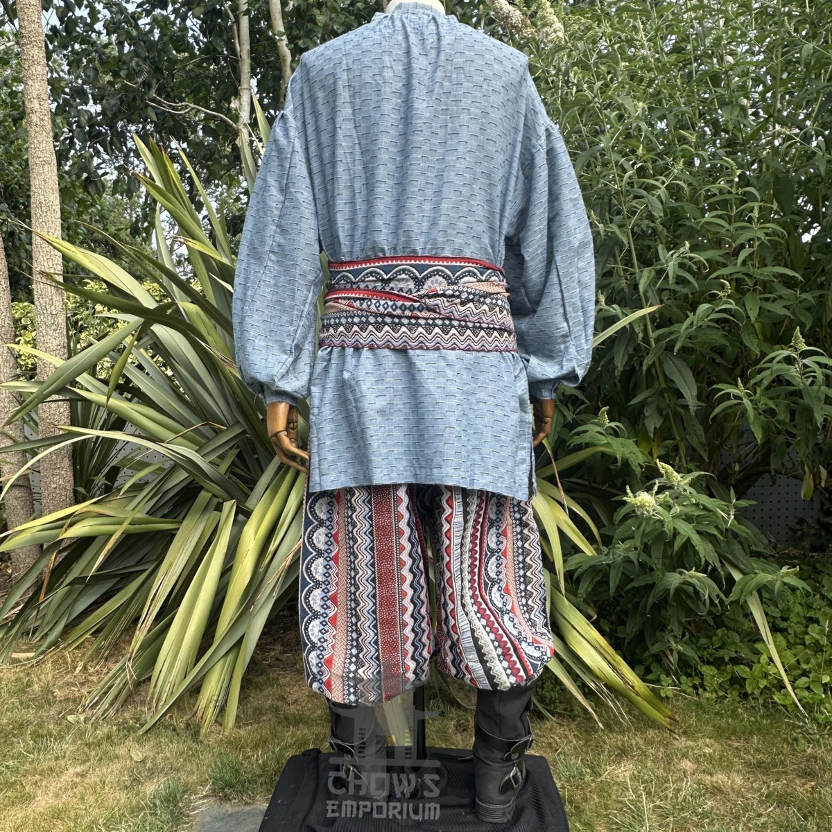 Blue medieval shirt, zigzag red sash, patterned pants, rear view, LARP outfit.