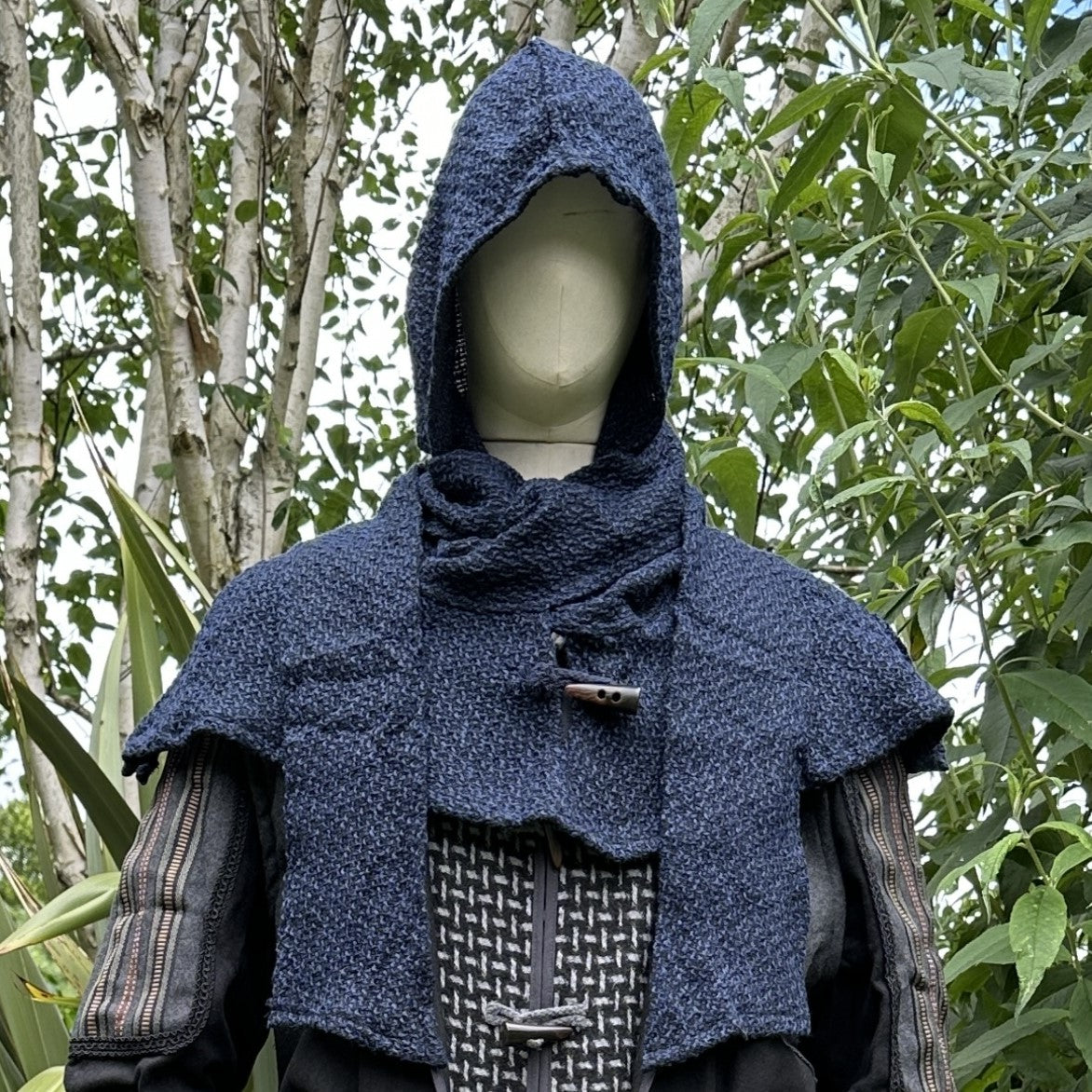 Mannequin in medieval LARP blue hooded cape with nature backdrop.