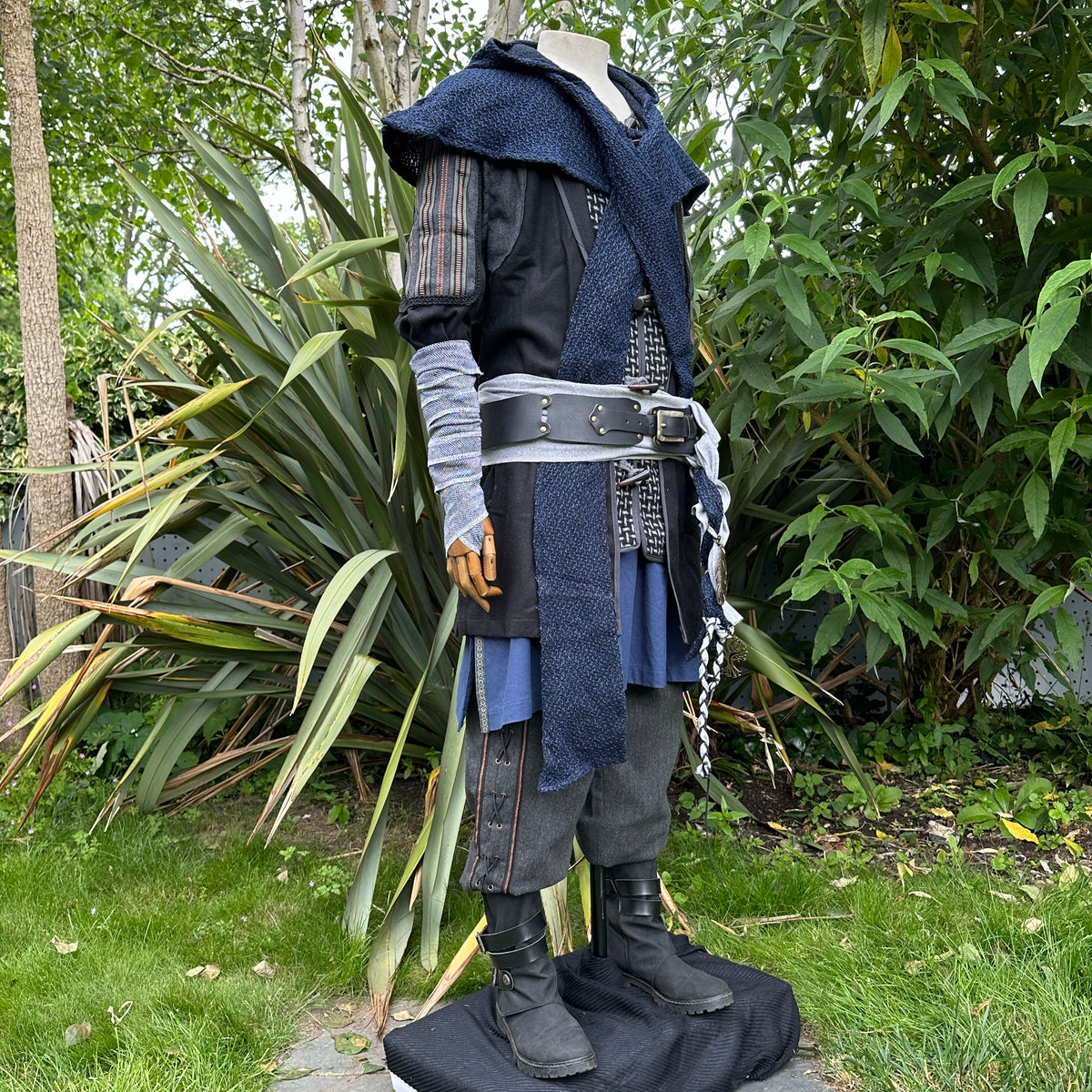 Medieval black jacket, blue hood, grey arm wraps on mannequin.