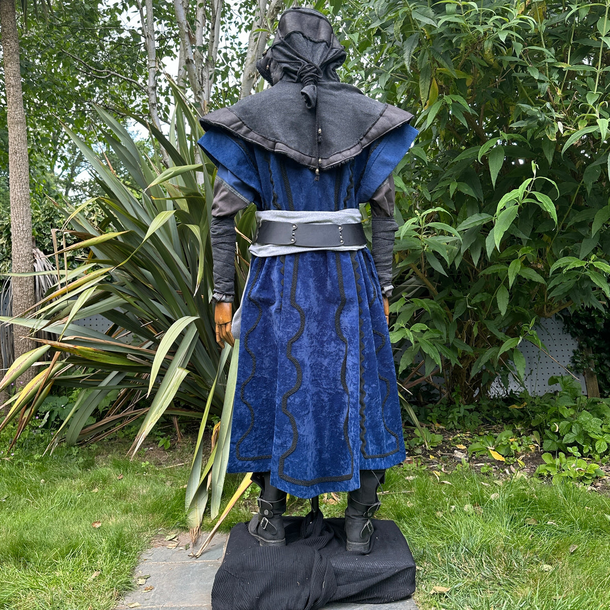 Medieval LARP costume back view, featuring a blue suede-effect panel waistcoat, black layered.