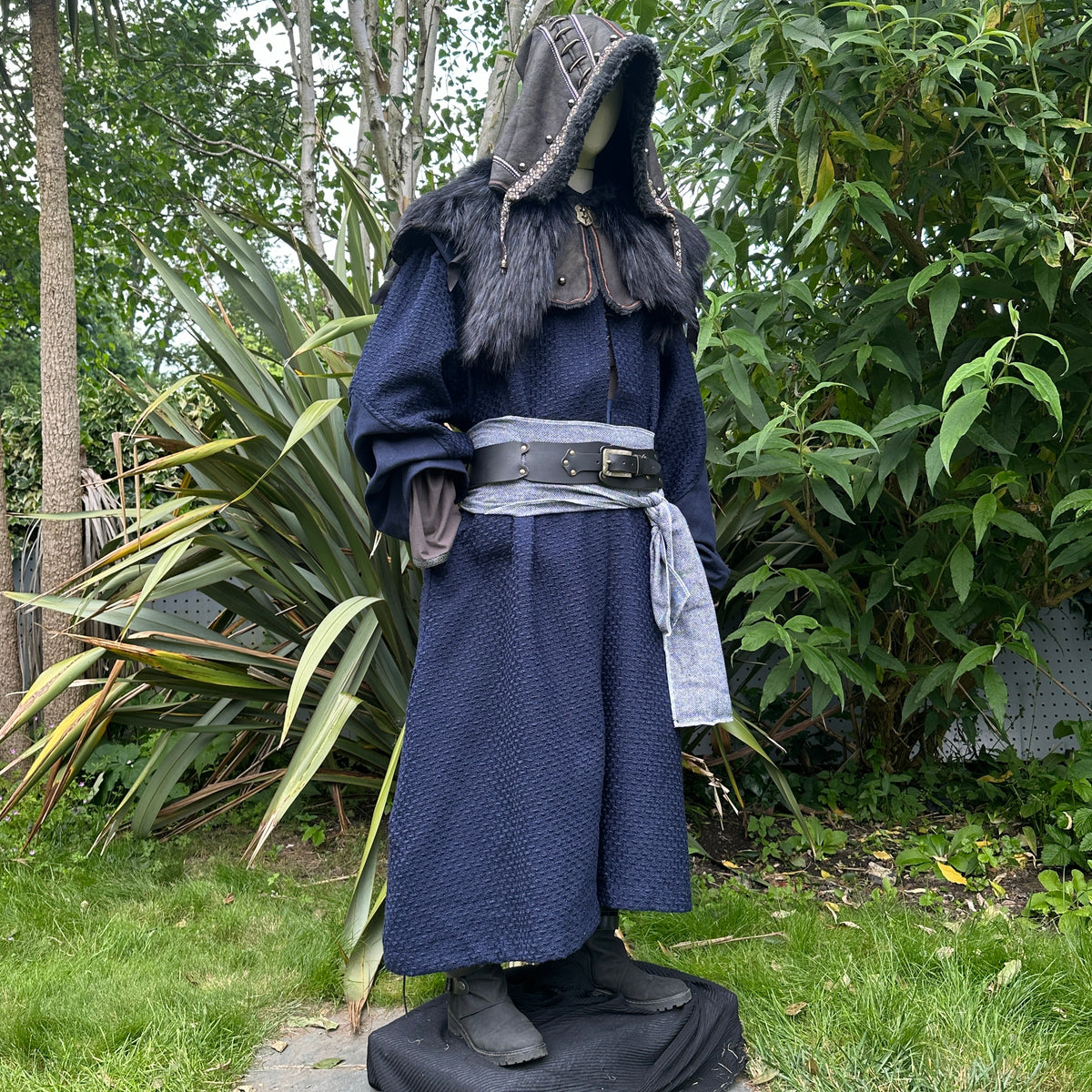 Blue medieval LARP robe and hood with black fur trim, grey belt, and sash, side view.