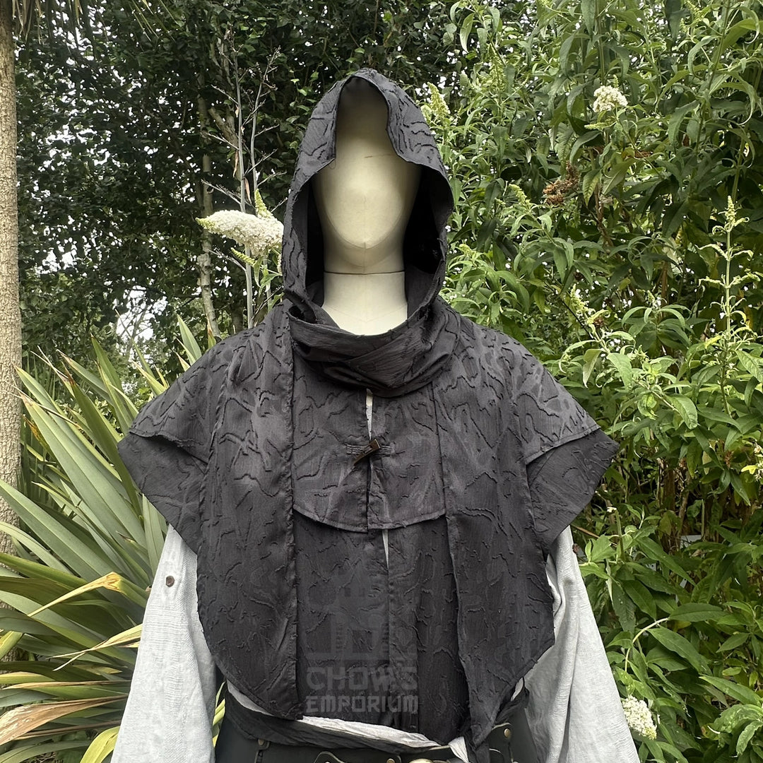 Close view of the black scarf hood worn up with the cowl gathered at the neck, shown with the waistcoat.