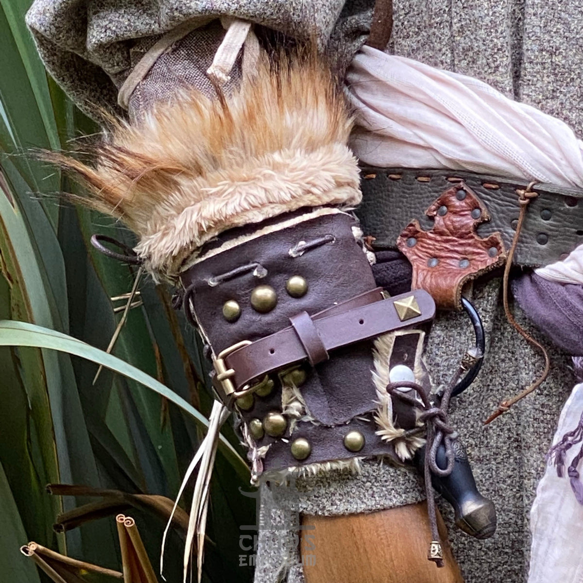 Brown leather medieval vambrace with fur lining and metal studs, close-up.