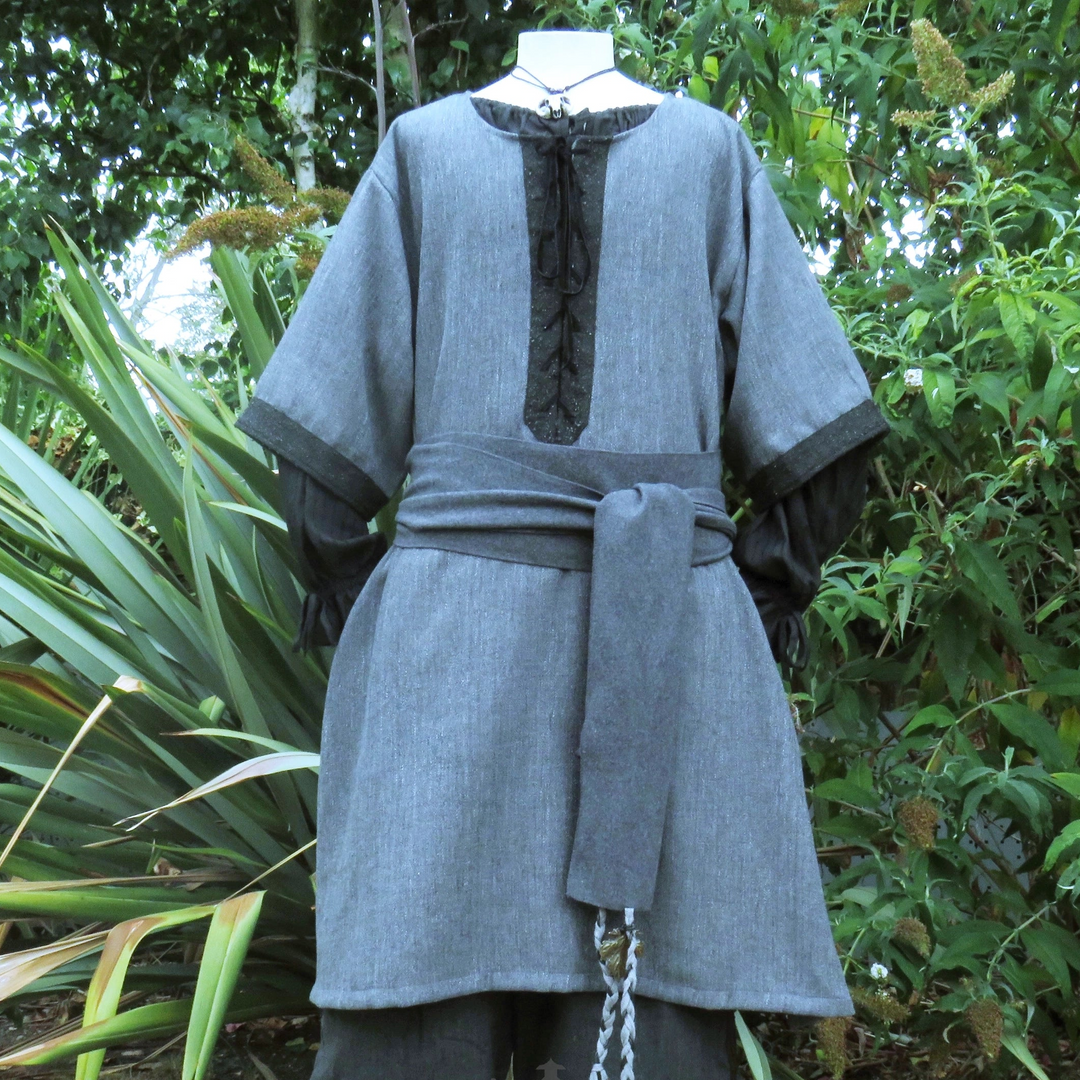 Grey and black woven medieval tunic, front view worn loose, showing the length and the black centre panel.