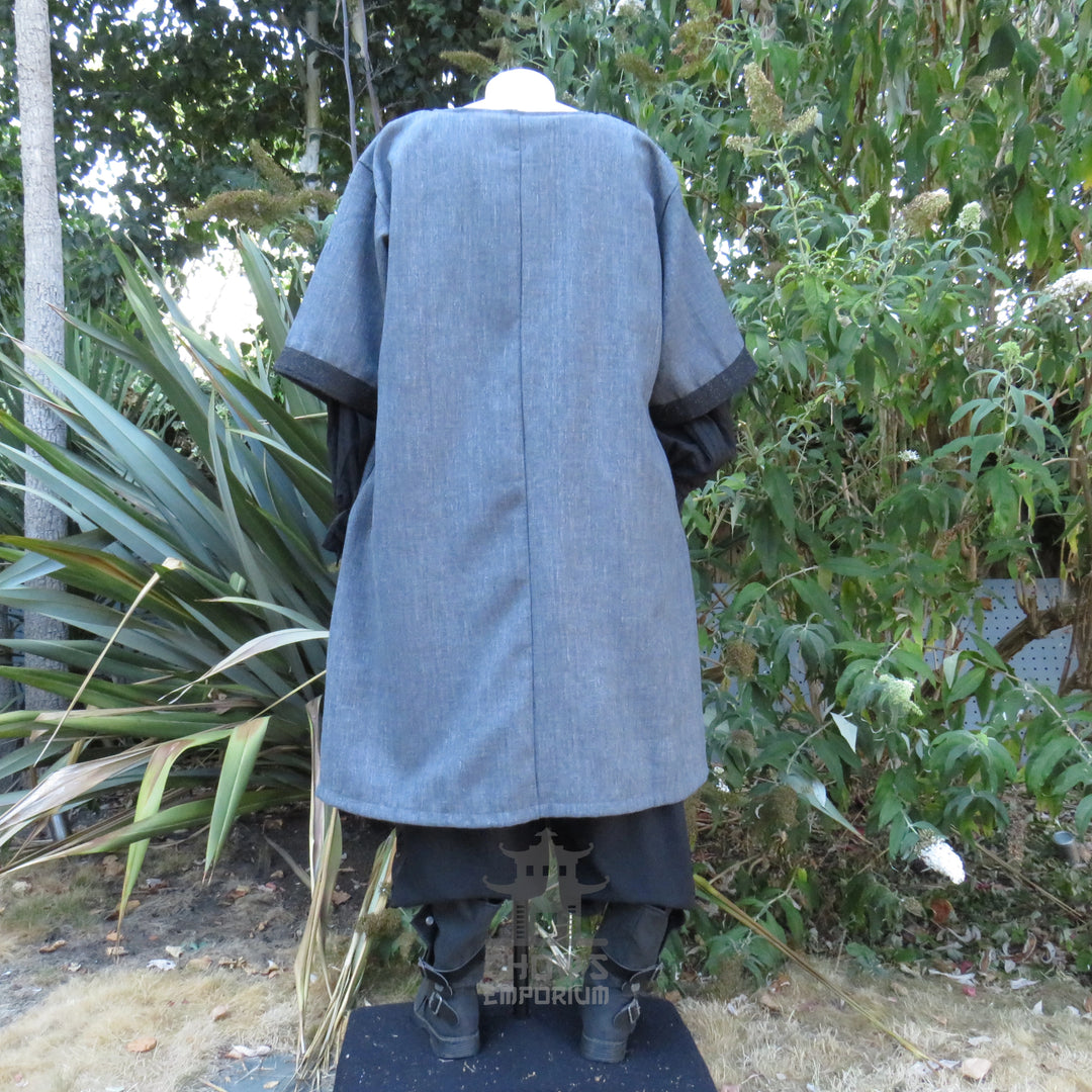 Grey and black woven medieval tunic, three-quarter front view showing the wide short sleeves and black cuffs.