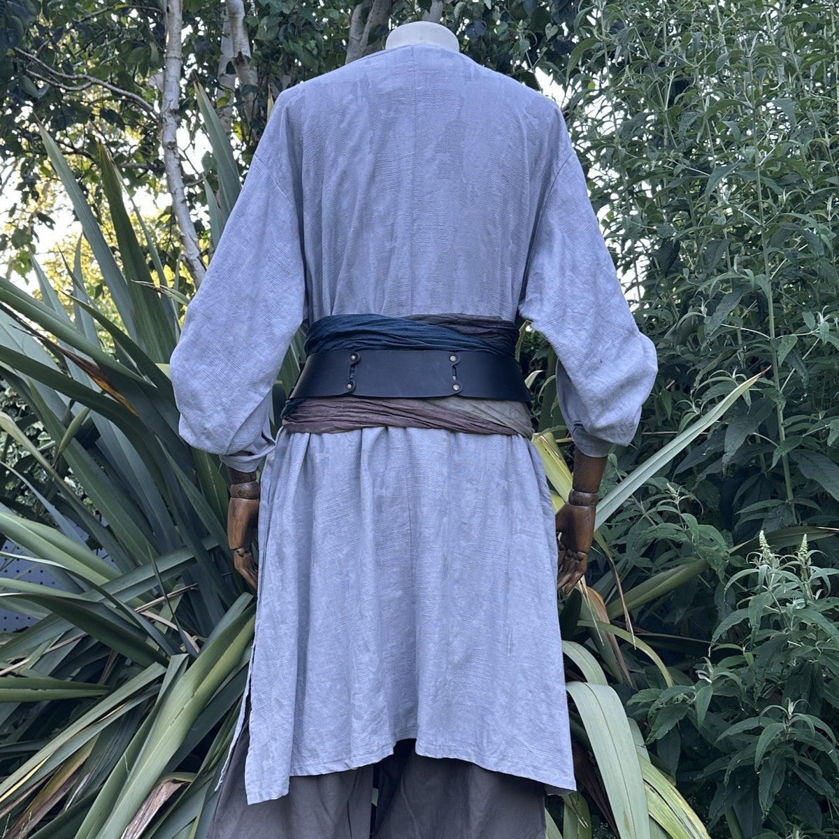 Back view of the grey V-neck cotton tunic with a wide black belt and sash tied at the waist, from the Phantom Duke noble outfit set