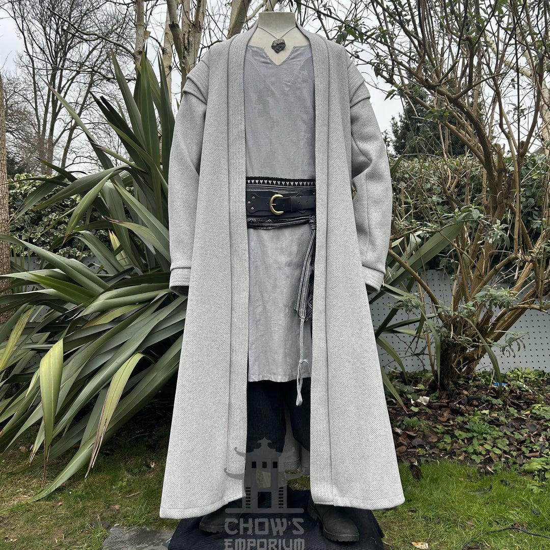 A light grey full-length robe,featuring a herringbone pattern displayed on a mannequin, shown from front view with black belt, in a garden setting.