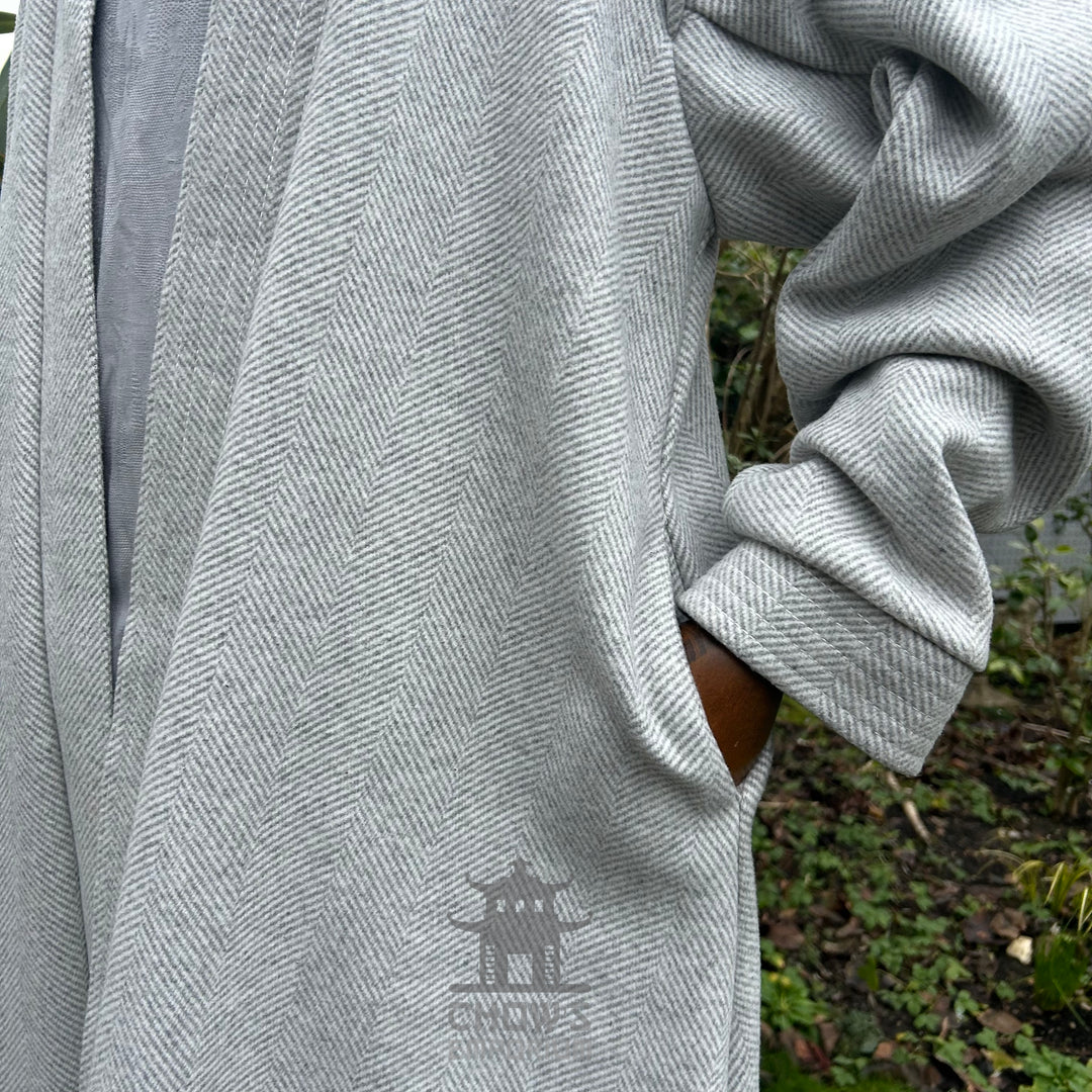 Sleeve and pocket detail on light grey herringbone robe with outdoor background.
