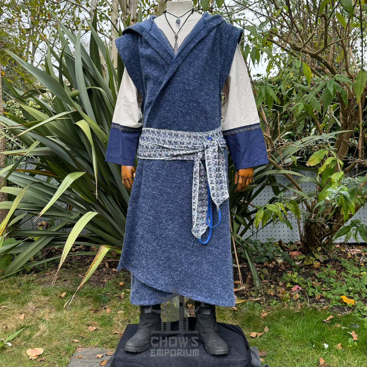 Mannequin wearing a blue robe with a patterned sash in a garden setting