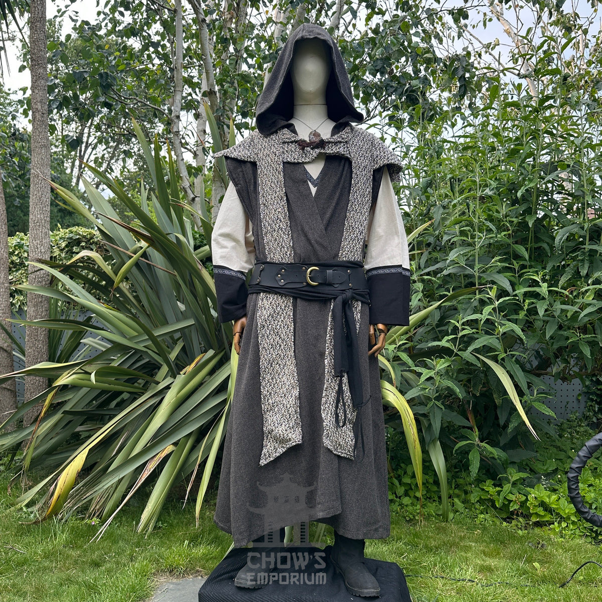 Front view of mannequin in hooded brown herringbone sleeveless robe with scarf hood, in garden setting.