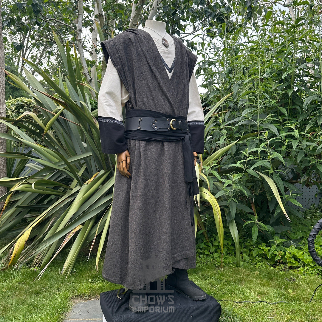 Side view of mannequin in hooded brown herringbone sleeveless robe with black belt, in garden setting.
