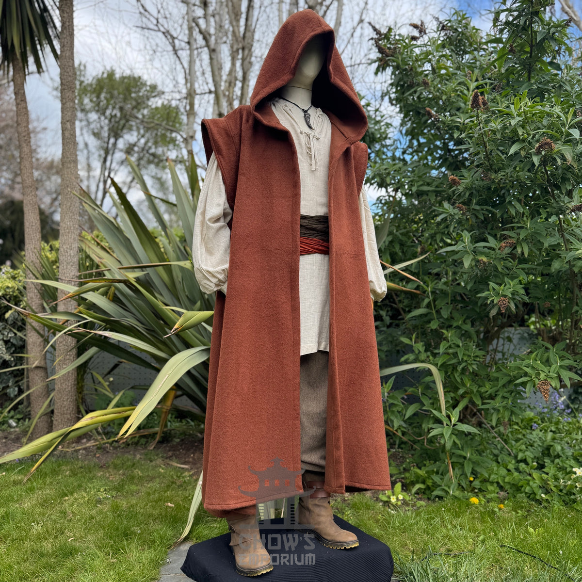 Mannequin wearing a long rust robe outdoors with greenery in the background