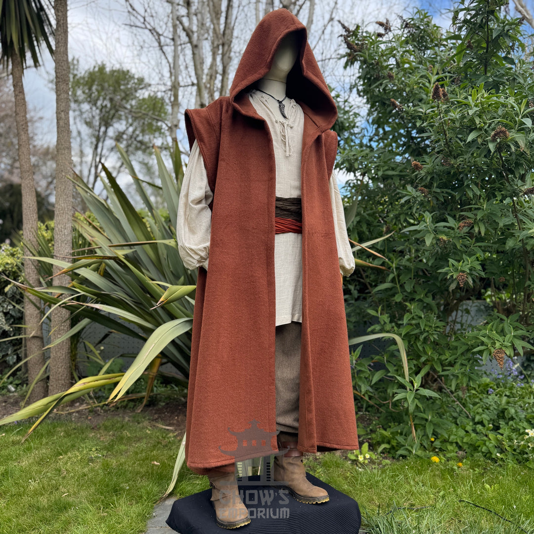 Mannequin wearing a long rust robe outdoors with greenery in the background