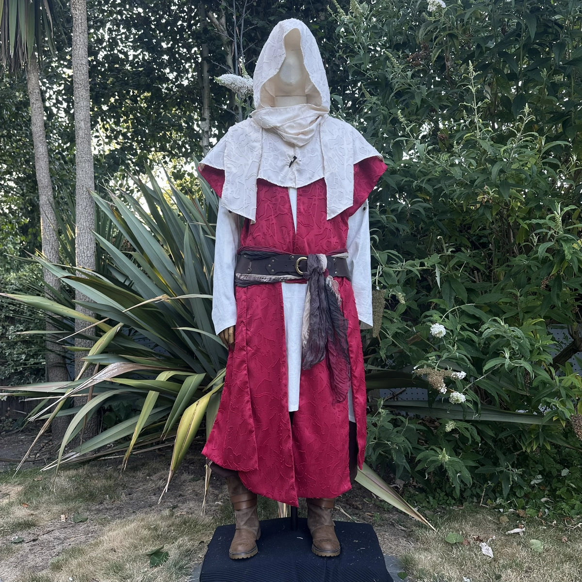 Cream hood and waistcoat worn up over a red layer, belted at the waist, front view. Belt sold separately.