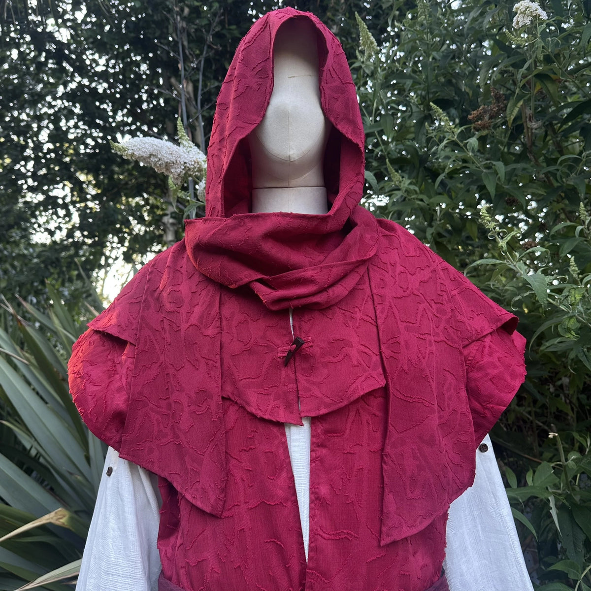 Close view of the red scarf hood worn up over the head and shoulders with the waistcoat.