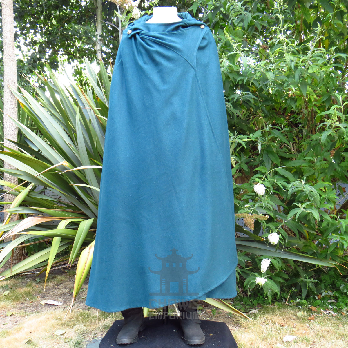 Teal hooded cloak fastened closed with the hood folded down at the back