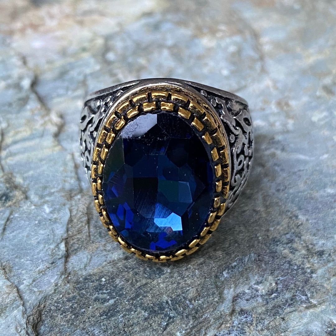Silver-gold ring with dark blue gem on stone surface for LARP.