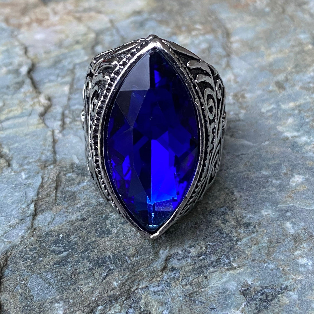 Silver ring with blue pointed oval stone, LARP medieval design on rocky surface.