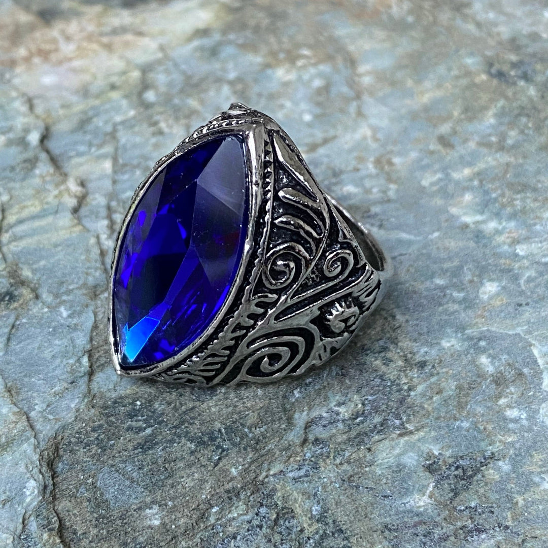 Silver medieval LARP ring with blue oval gemstone on stone surface.