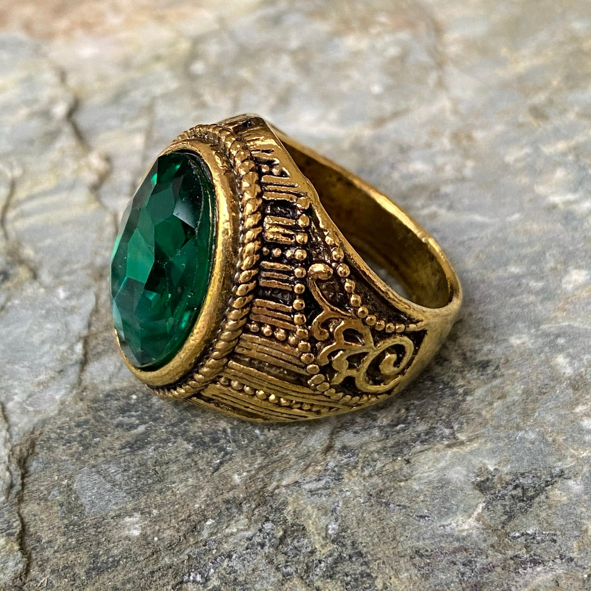 Gold ring with a green gem, intricate medieval design, side view for LARP.