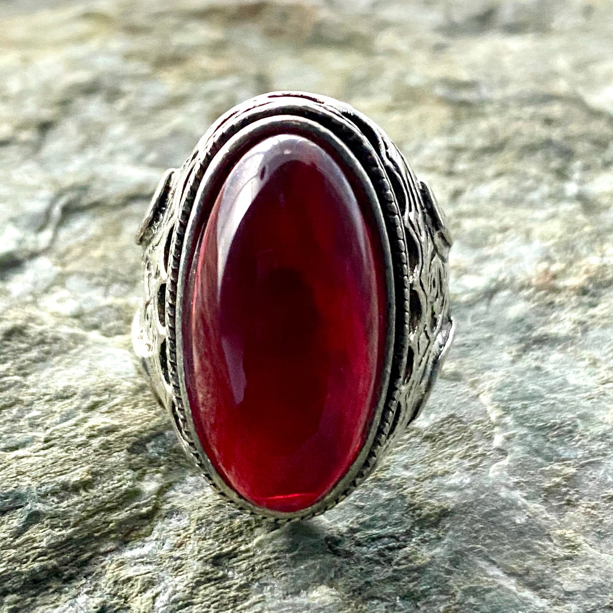 Silver ring with red gemstone, ornate design for medieval LARP enthusiasts.