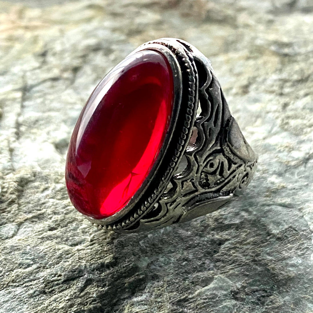 LARP ring with ornate silver band set with large red gemstone, side view.