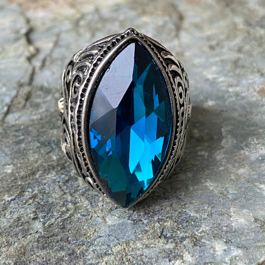 Turquoise ring with ornate medieval band on textured stone background.