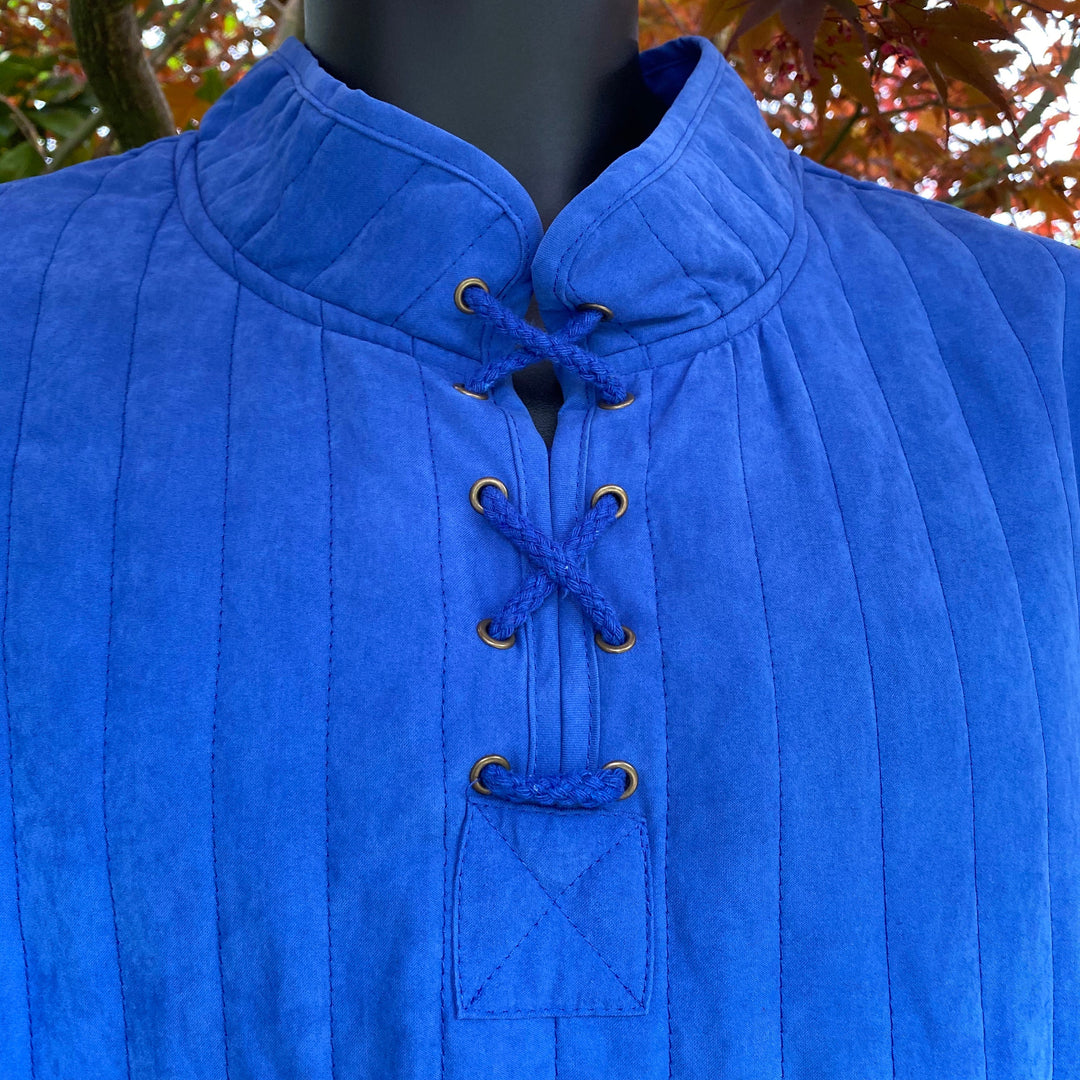 close up quilted effect, high collar and lace up detail on blue cotton gambeson.