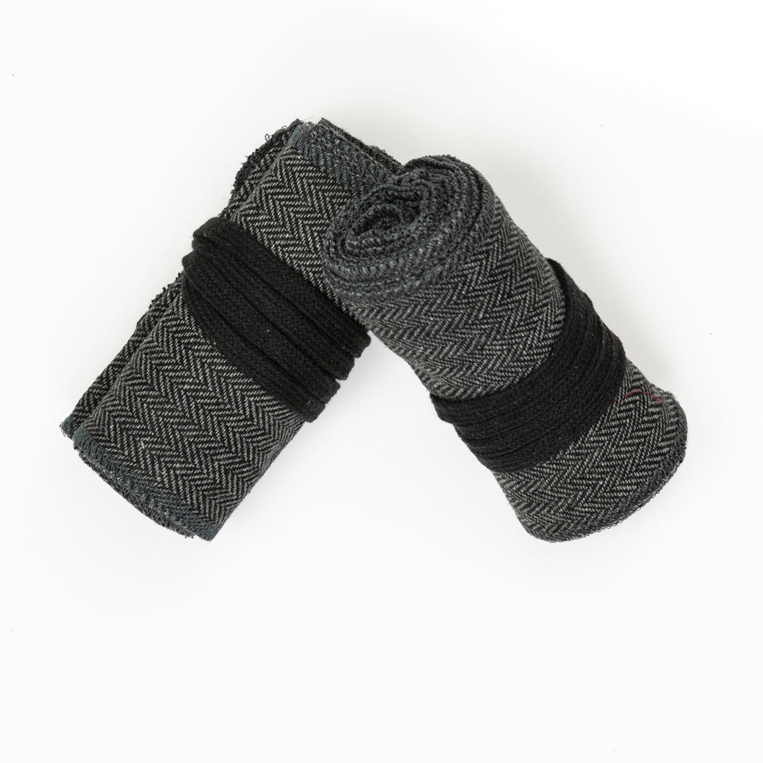 Grey herringbone leg wraps for medieval LARP, rolled with black ties.