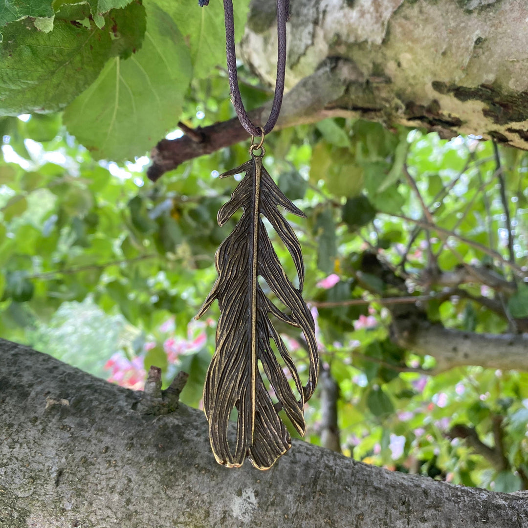 Brass feather necklace on cord, hanging in tree, medieval LARP accessory.