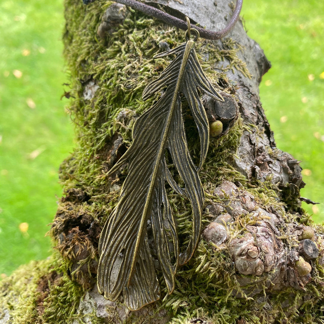 LARP brass feather necklace on mossy tree, medieval cosplay accessory.