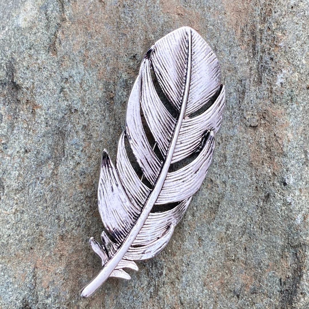 Silver feather brooch on stone background for LARP.
