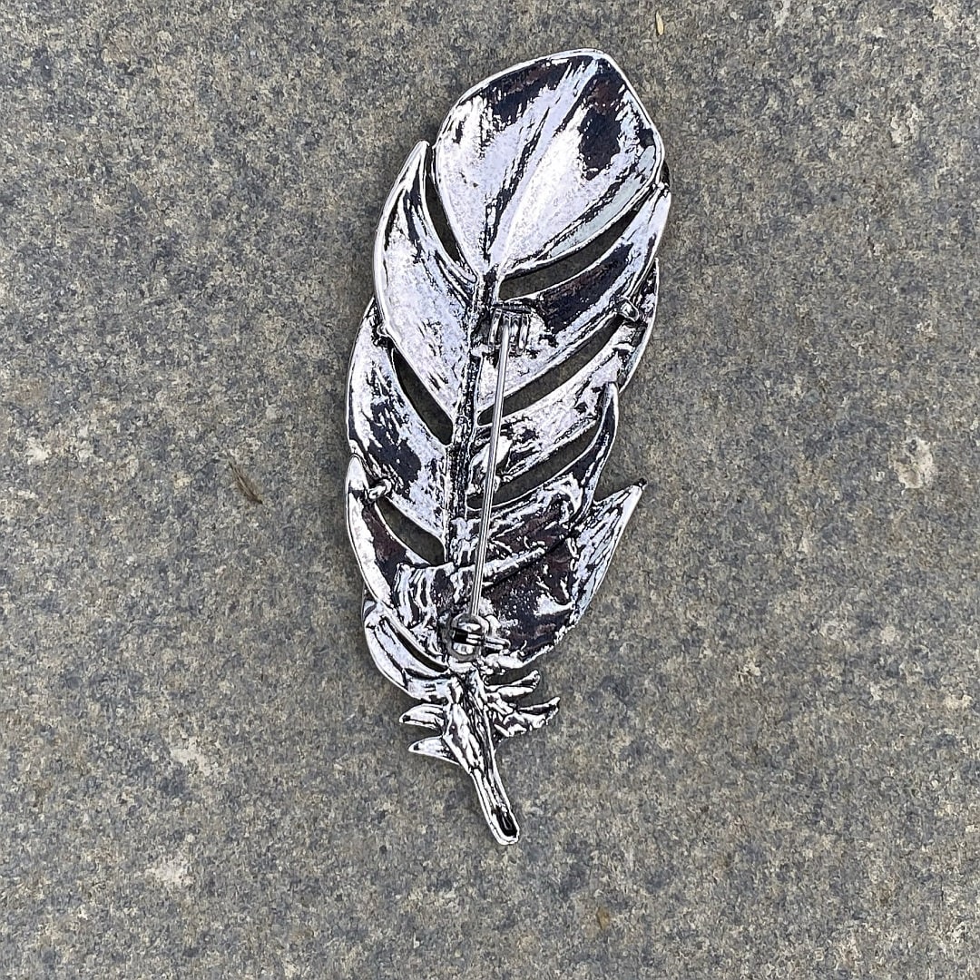 Silver feather brooch on stone background, detailed for medieval LARP attire.