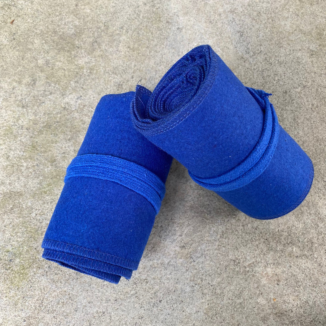 Blue wool leg wraps for medieval LARP, rolled on stone surface.