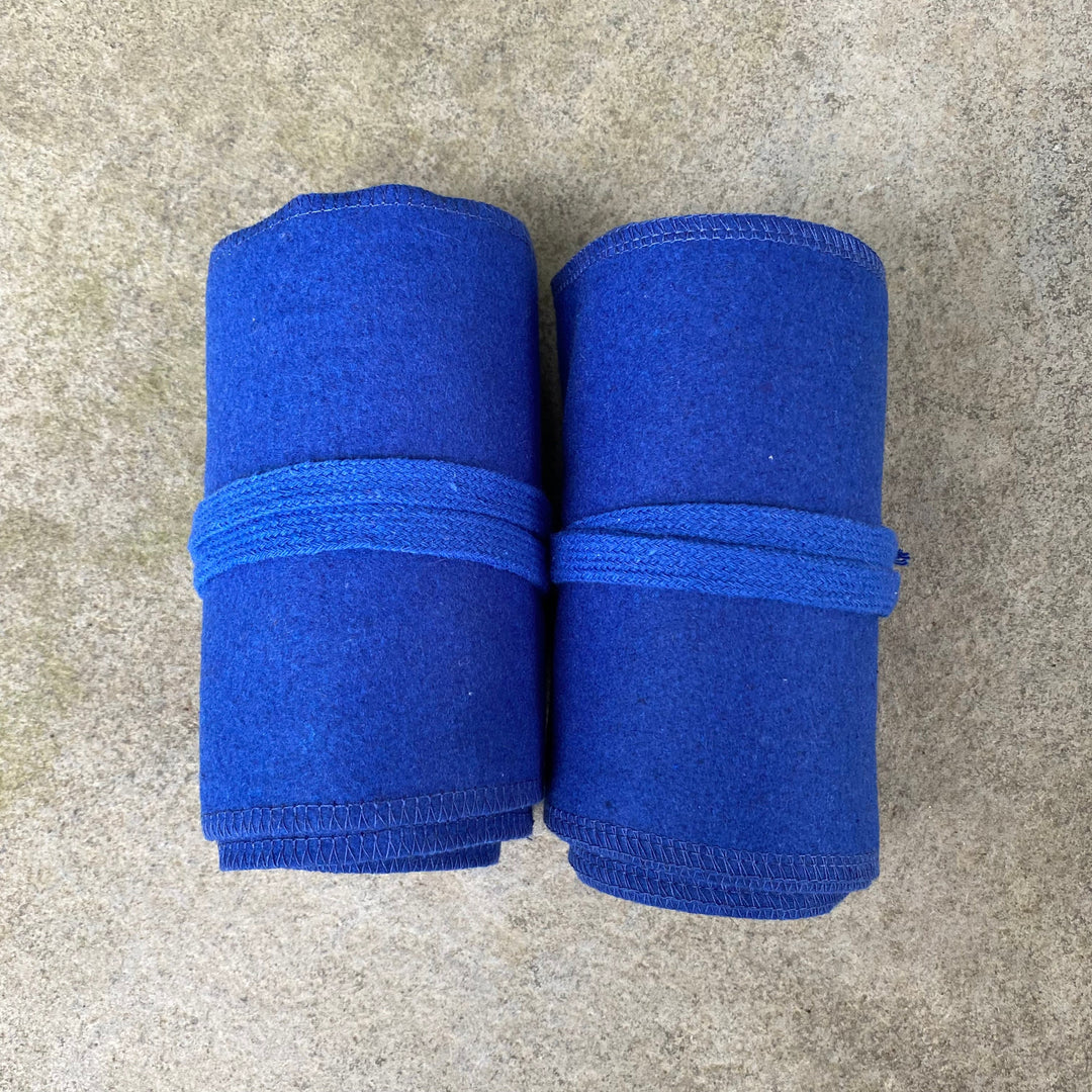 Two neatly rolled blue wool leg wraps on a stone surface for medieval LARP.